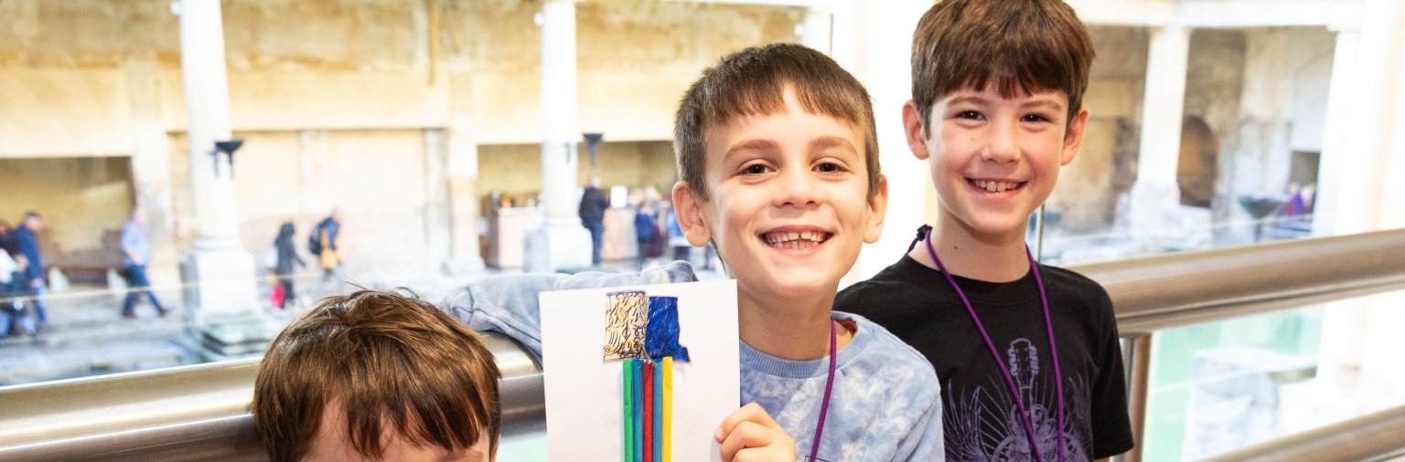 Three boys at the Roman Baths holding up their crafts